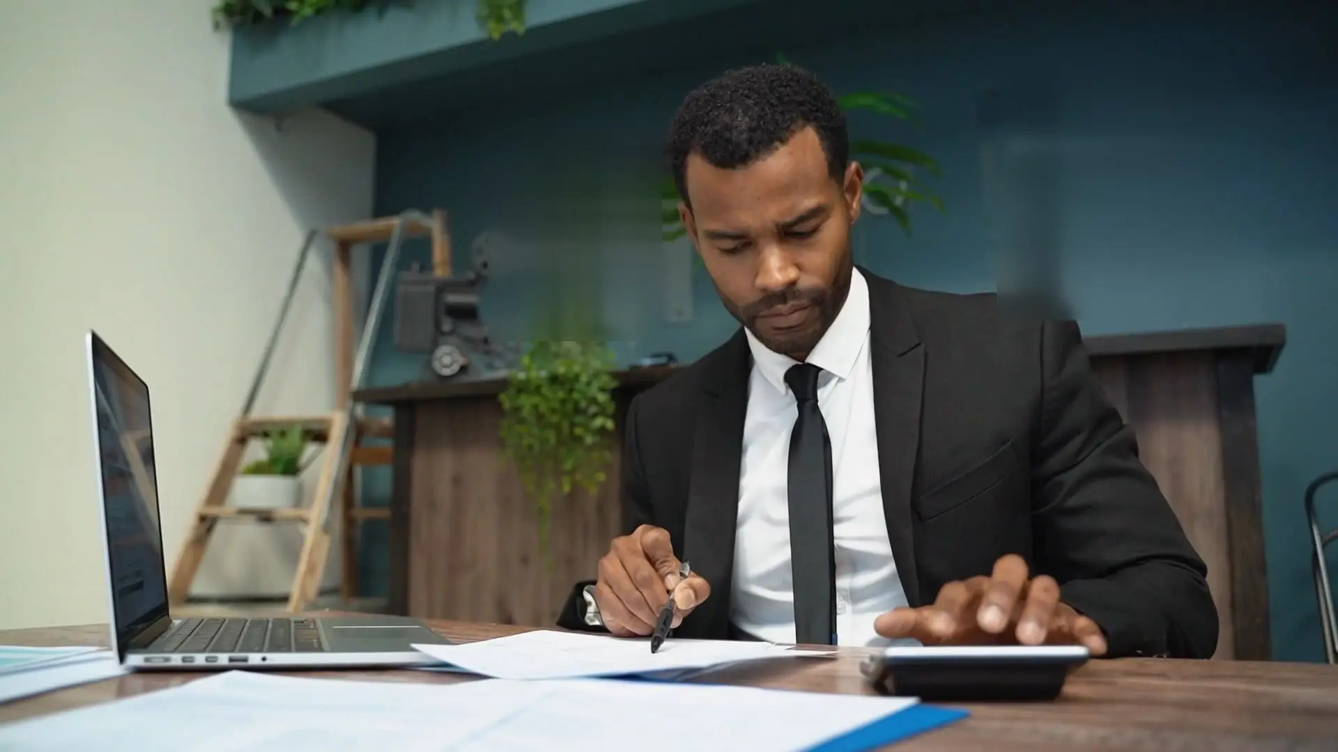 A finance professional checking invoices with a calculator at his desk.